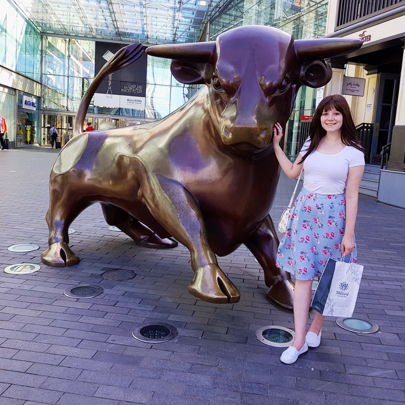 Sam is stood with the bull statue outside the Bullring shopping centre in Birmingham
