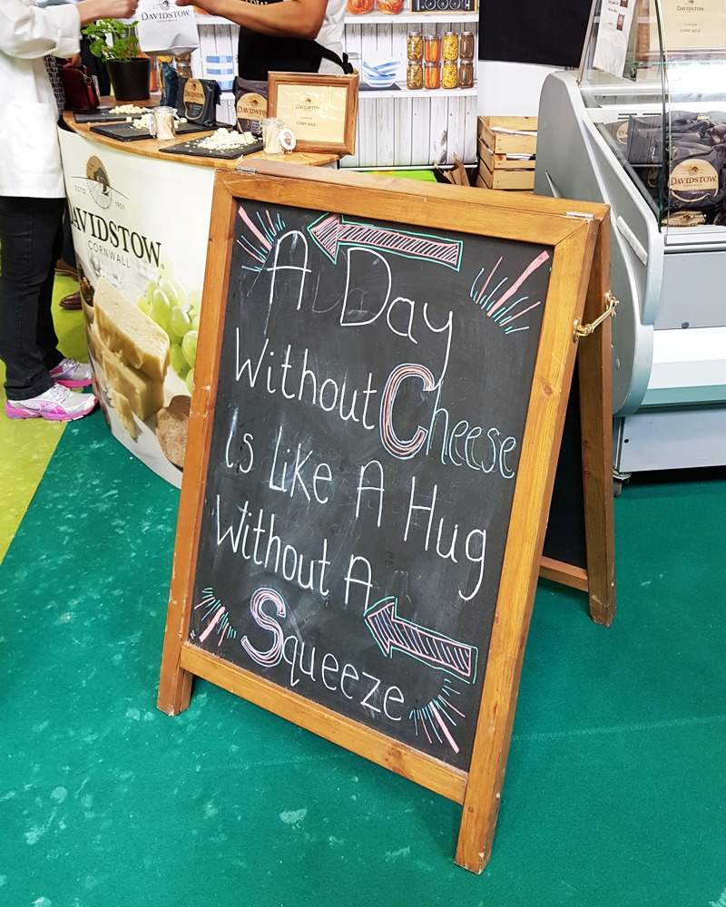 Sign at BBC Good Food show which reads "A day without cheese is like a hug without a squeeze"