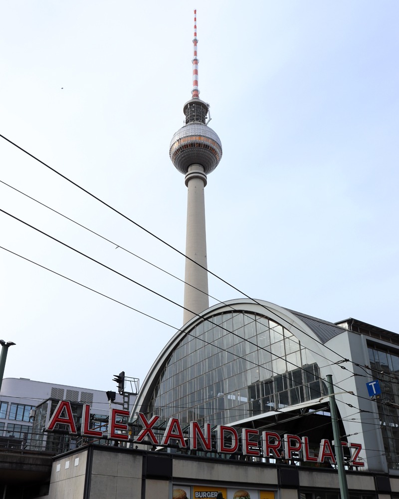 Alexanderplatz train central. The TV tower is visible in the background against the bright blue sky.