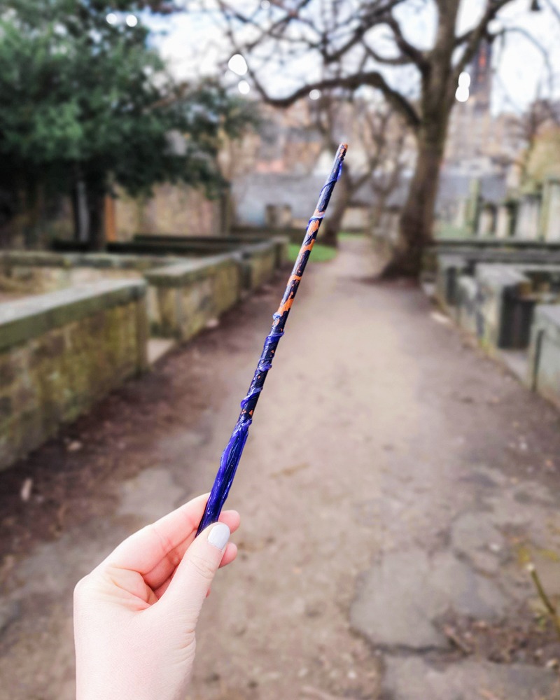 Sam is holding a plastic blue wand which was given to her on the free Harry Potter tour of Edinburgh. She is pointing it at Greyfriar's Kirkyard
