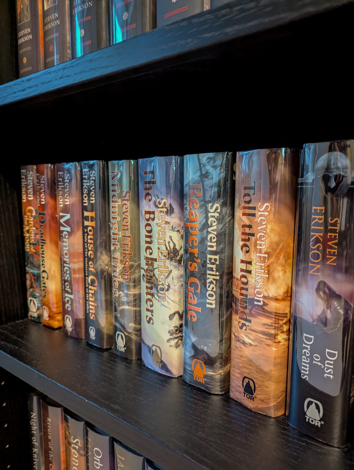 Malazan Book of the Fallen series - the original hardbacks on a dark wood bookshelf